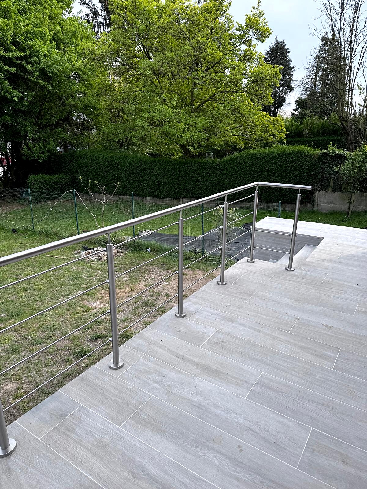 Garde-corps inox à barres sur terrasse donnant sur un jardin